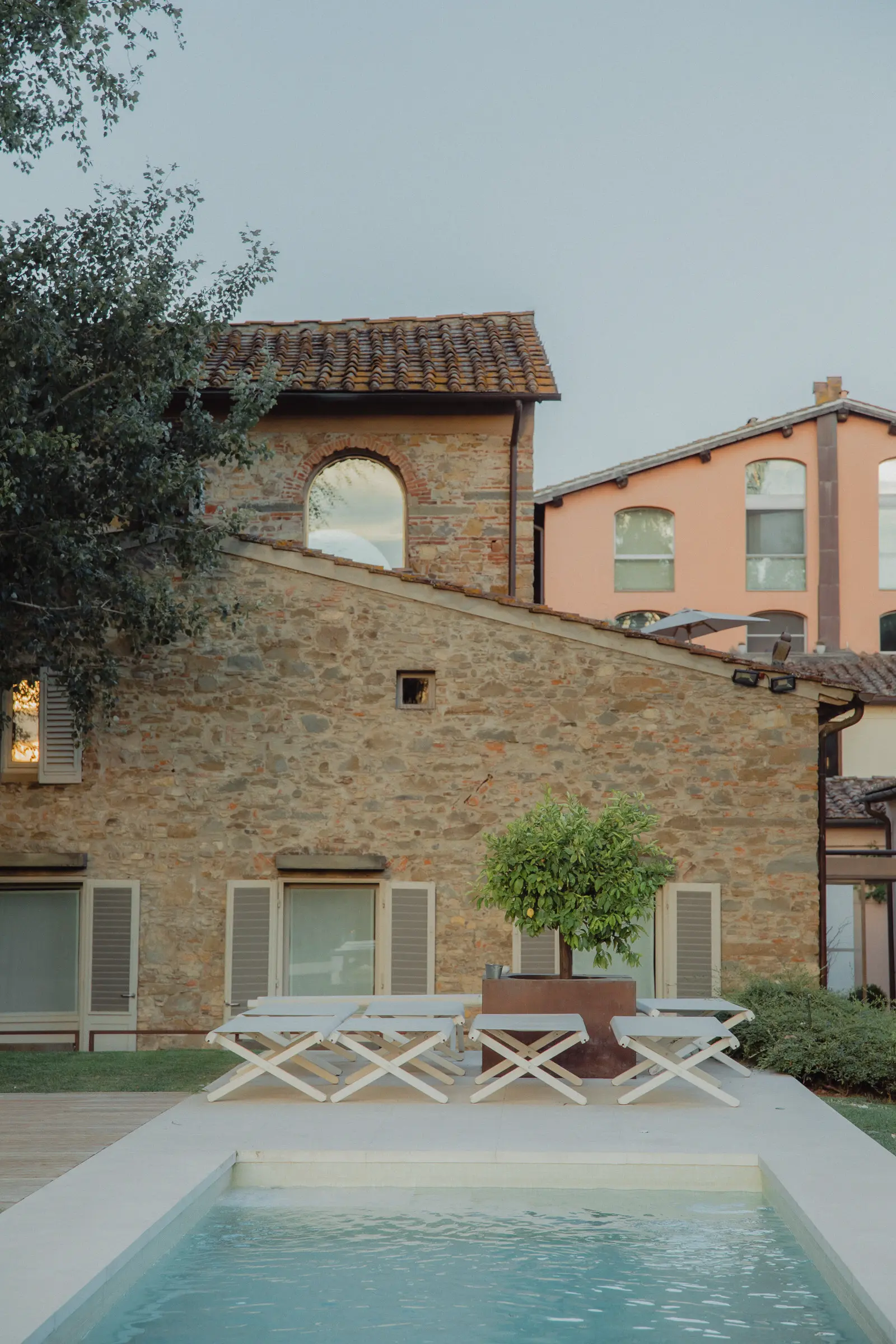 Outdoor hospitality photography at Riva Lofts Florence featuring a contemporary garden restaurant, pool reflections, cocktails, natural light, and relaxed boutique hotel atmosphere in Florence, Italy.