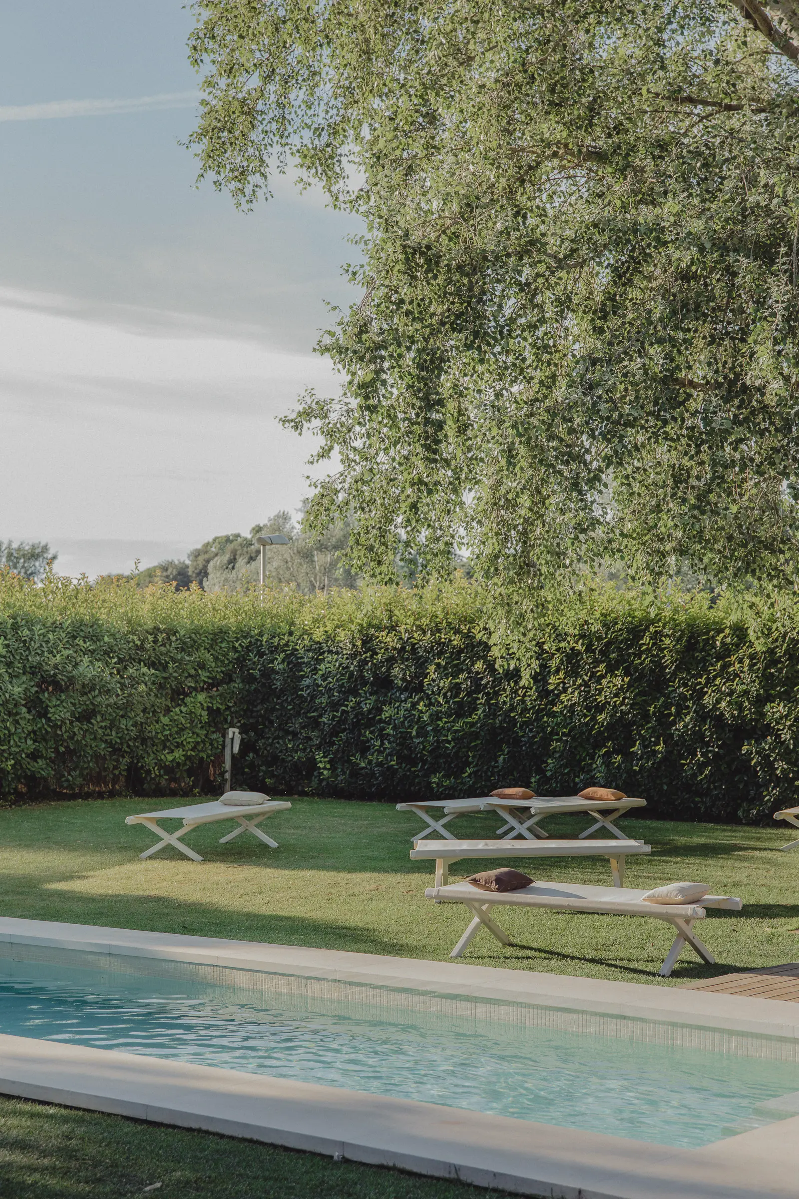 Outdoor hospitality photography at Riva Lofts Florence featuring a contemporary garden restaurant, pool reflections, cocktails, natural light, and relaxed boutique hotel atmosphere in Florence, Italy.