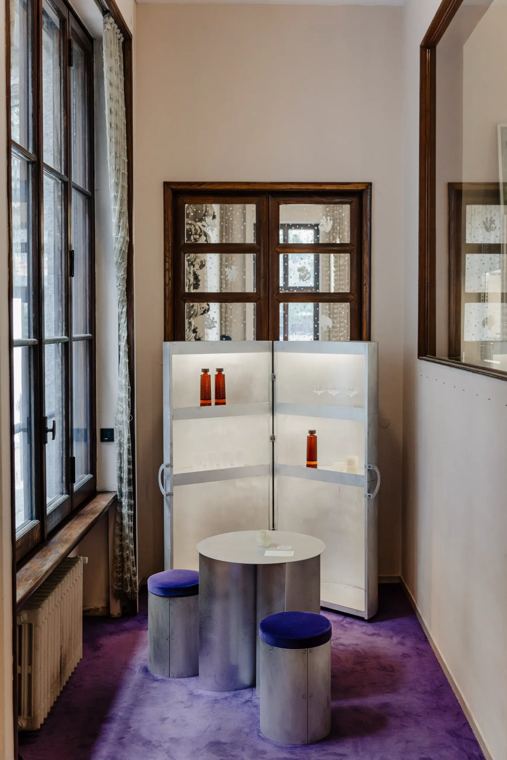 Atmospheric contemporary design installation at Alcova Milan with experimental interiors, sculptural objects, raw textures, and dramatic architectural light.