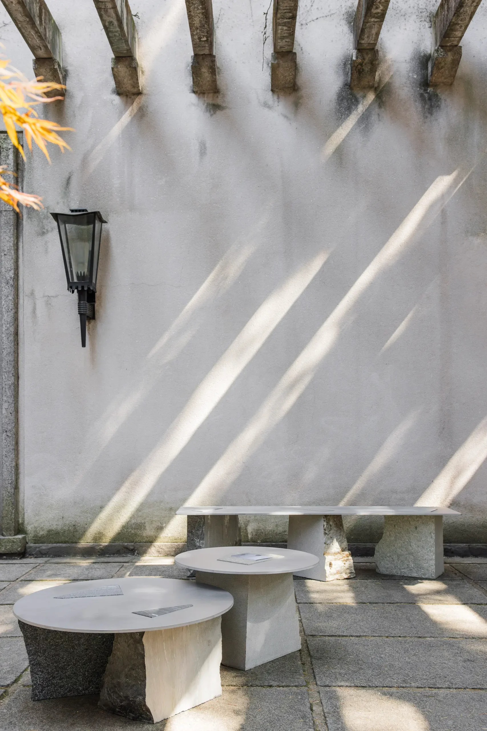 Atmospheric contemporary design installation at Alcova Milan with experimental interiors, sculptural objects, raw textures, and dramatic architectural light.